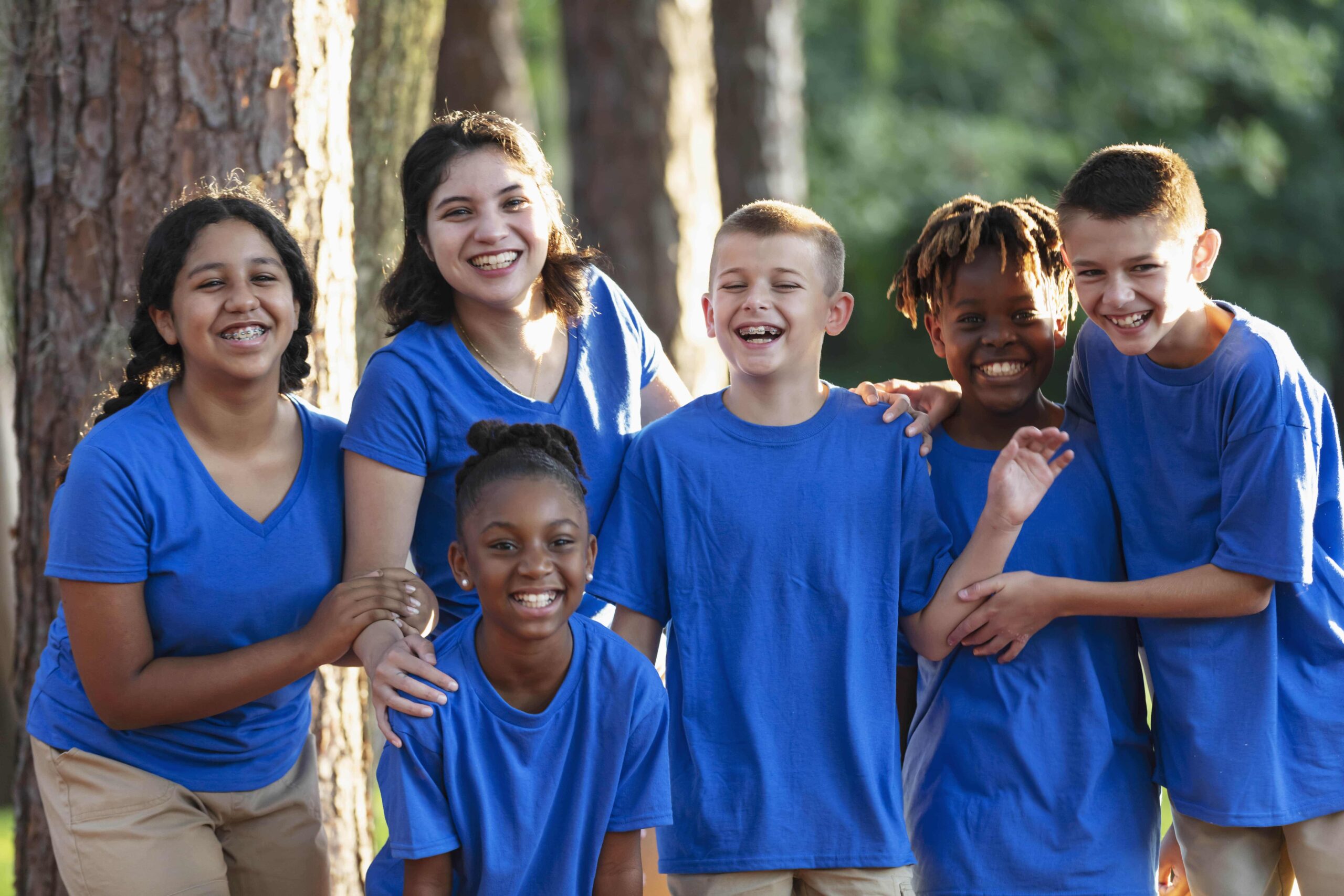 Group of kids wearing blue shirts smiling.